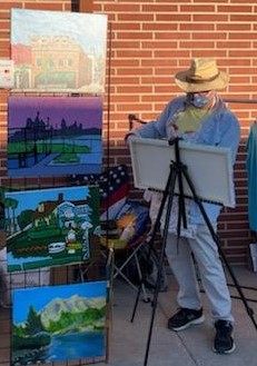 Oscar Will painting next to display of paintings